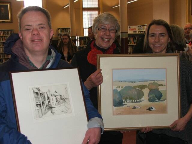 REMEMBERING BILL: Isabel Gribble (middle) with son Robbie and daughter Cate holding the art of community-worker Bill Gribble which they donated to the Ballaarat Mechanics' Institute.