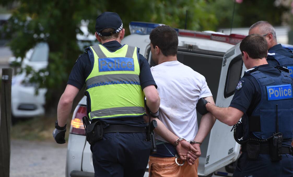 Police take a man into custody after the manhunt. It is believed he was bitten on the shoulder by the police dog. Picture: Lachlan Bence.