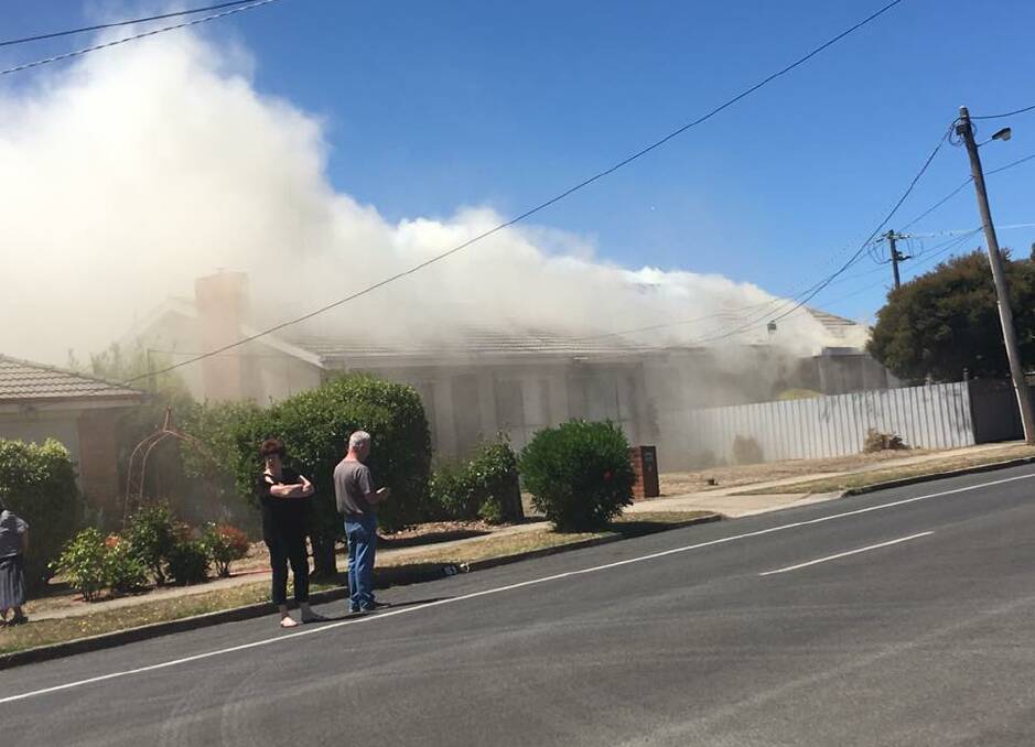 Neighbours watch on as smoke billows out of the house. Picture: via Facebook.