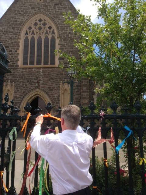Bishop Paul Bird ties a ribbon at St Patrick's Cathedral. 