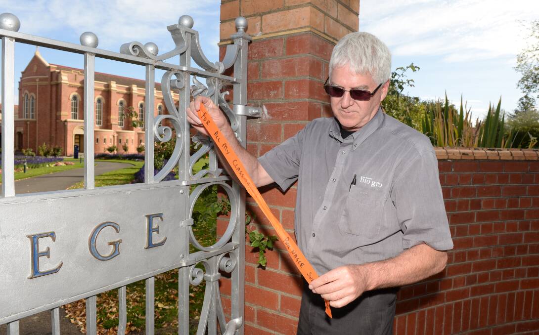 SUPPORT: Clergy sex abuse survivor Phil Nagle removes a ribbon he tied to the front gates of St Patrick's College. Picture: Kate Healy. 