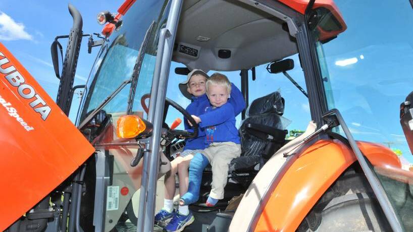 DRIVER'S SEAT: Bill Yeo and Max Butler get into prime position of a Kubota tractor at the Australian National Field Days. Photo: JUDE KEOGH