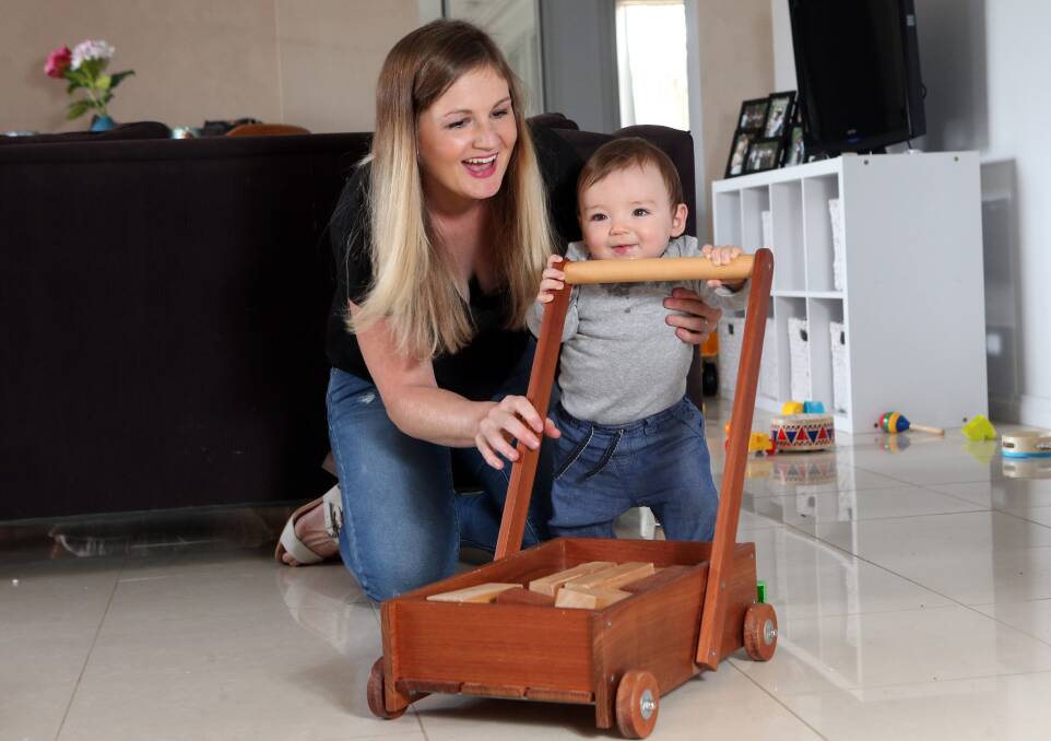SUPPORT: Sarah Hocking guides nine-month-old son Archer as he finds his feet pushing a wooden cart that was lovingly made by a family member. Picture: GLENN DANIELS