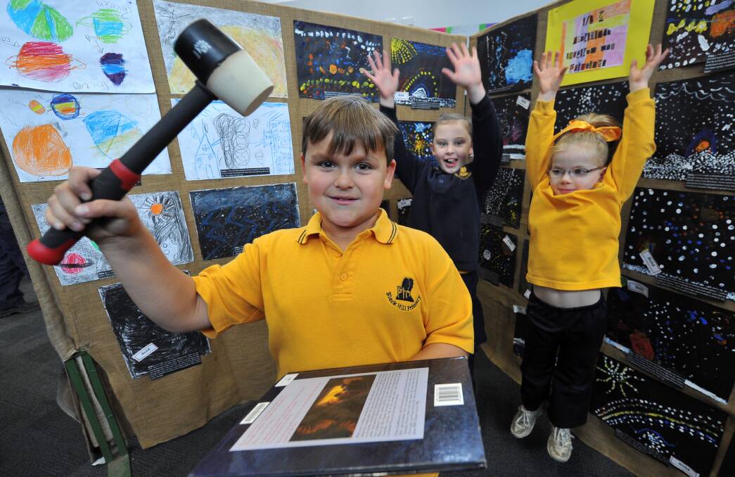 SOLD: Black Hill Primary School pupil Luke Atkinson, 8, holds the auction hammer while Amelia Rudd, 7, and Erica Jones, 6, celebrate the fundraiser. Picture: Lachlan Bence