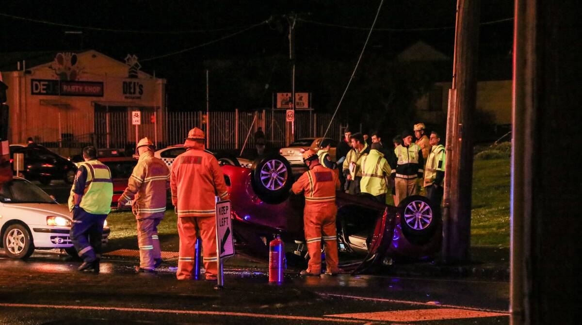 CAR SMASH: Emergency services help a young woman, aged in her 20s, after her car crashed into a power pole and flipped. Picture: Contributed 