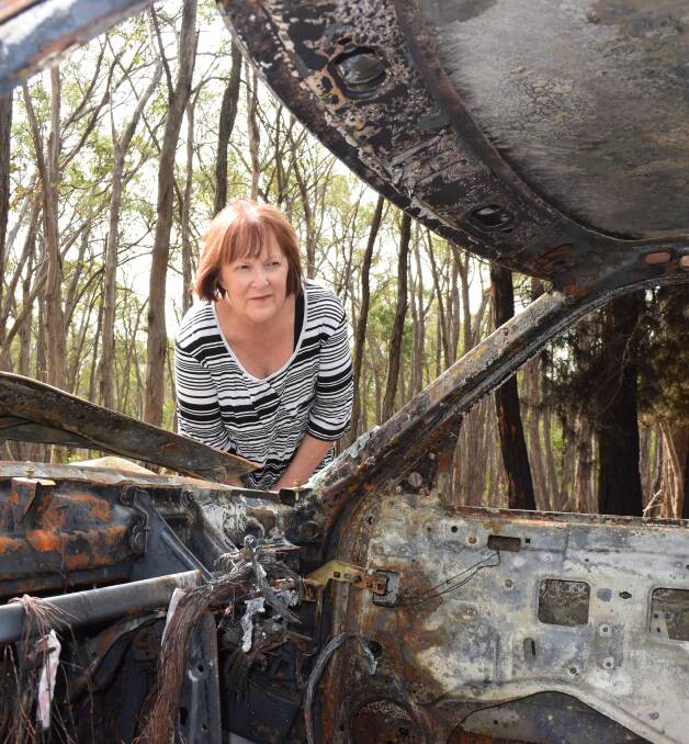 GUTTED: Lynette Cartledge inspects the torched car which was engulfed by flames which shot up a nearby tree. Picture: Olivia Shying 