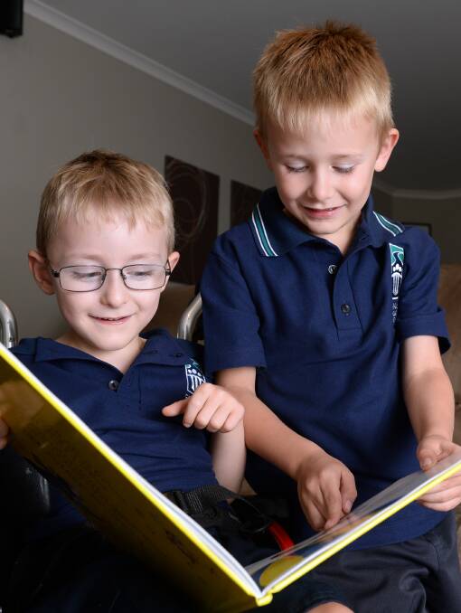 BROTHERLY LOVE: Archie, 4, and Jake Sims, 6, read a book together and have a chat about Archie's first day of school last week. Picture: Kate Healy 