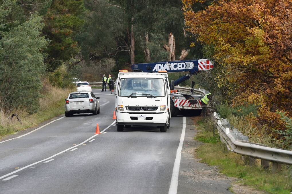 CLOSE CALL: Police redirect oncoming traffic while workers retrieve the female P-plater's Nissan dual-cab from a ditch on Thursday afternoon. Picture: Kate Healy 