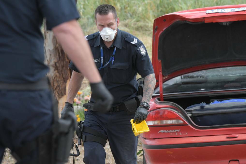 A policeman inspects the dumped Ford that was used to allegedly ram officers in Maryborough.