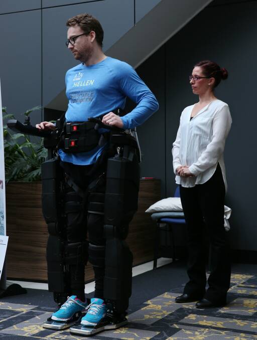 ON HIS FEET: Paraplegic Louis Rowe stands up using the pair of user-operated robotic legs, dubbed "Hellen", at the University of Newcastle. Picture: Simone De Peak