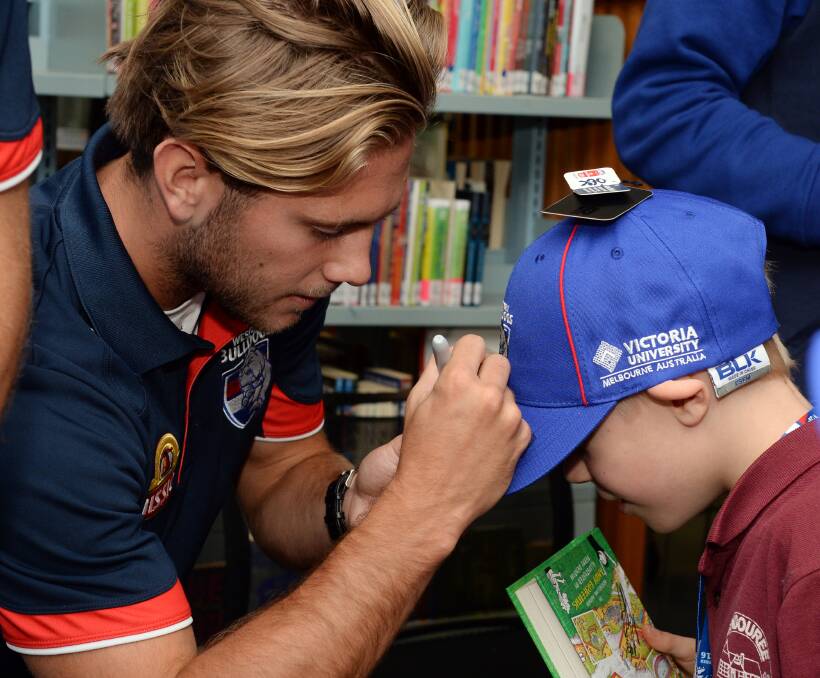 SIGNING ON: The Bulldogs are making a big play in community programs about Ballarat, including Bulldogs Read with Caleb Daniel offering grade three pupil Jimmy Jones a little extra encouragement this week. Picture: Kate Healy