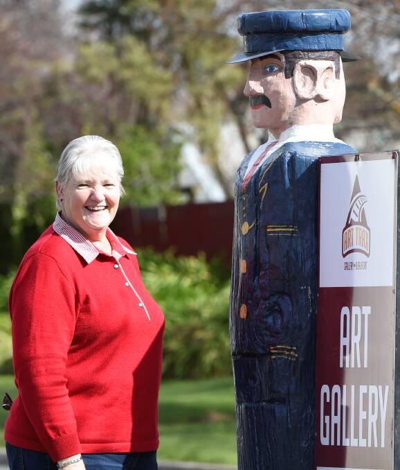 ICONIC: Pyrenees Art Council's Anne Beer pops by Harry the station master bollard as he makes a stand, hoping to be popular with locals and tourists, in Beaufort. Picture: Lachlan Bence