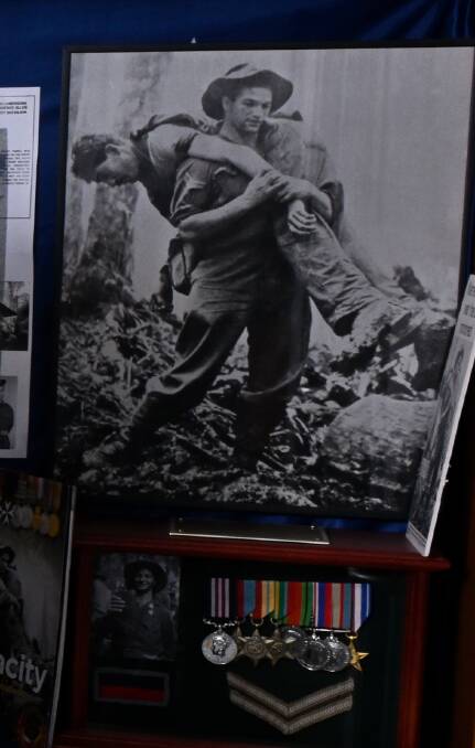 The iconic photo of Corporal Leslie "Bull" Allen carrying an unconscious American soldier from the battlefield at Mount Tembu in July 1943. The image is on display with Allen's medals at Ballarat RSL.