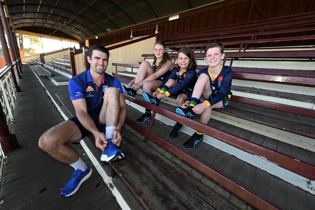 Western Bulldog 2016 AFL premiership captain Easton Wood tries new boots on for size with Lake Wendouree juniors Lexie Seamons (age 13), Flynn Hanrahan (10) and Lewis Warland (11) at City Oval on March 20, 2024. Picture by Lachlan Bence.