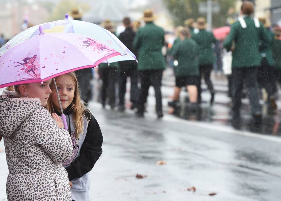 REMEMBER: Six-year-olds Emelia Coyle and Zahra Winduss gather under shelter to watch the Creswick Anzac Day march. Picture: Kate Healy