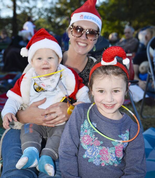Feeling festive: Lucas Cornell, 1, Zara Smith and Jessie Cornell, 5, enjoy the sounds of the Ballarat Carols at North Gardens on Sunday evening.  Picture: Dylan Burns. 
