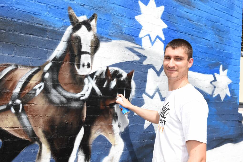 New mural: Alex Hendricks at work on his mural which decorates the exterior of a Ballarat dental practice. Picture: Kate Healy.