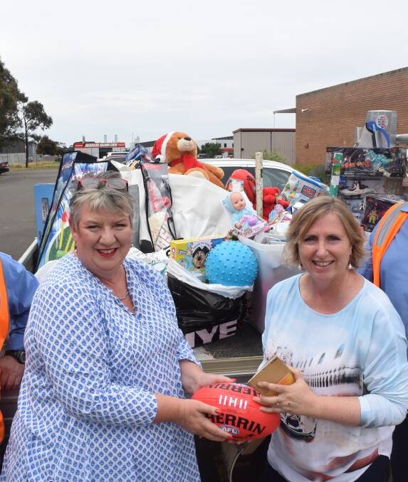 HANDBALL: City of Ballarat chief executive Justine Linley passes a ute-full of gifts to Pinarc chief executive Marianne Hubbard so that children and adults with disabilities will have a happier Christmas. Picture: Cameron Brooks