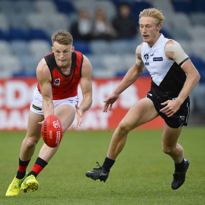 PURSUIT: Essendon young gun Mason Redman gathers possession as Roosters' Mitch Rodd looks to apply pressure.