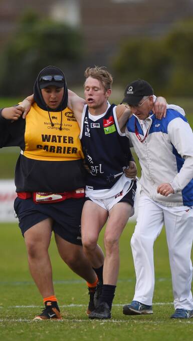 INJURY: Nick Hind is helped off the ground by Ballarat Football League trainers after hurting his ankle on Saturday. Picture: Luka Kauzlaric.