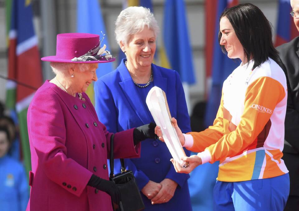 Retired Australian cyclist Anna Meares receives the Commonwealth Games relay baton from Queen Elizabeth II at Buckingham Palace on March 13. Picture: AP
