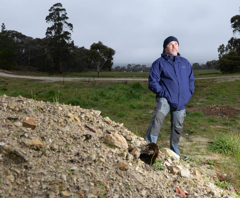 Rubbish: Duggan Street resident Mark Hosking with a pile of rubbish unearthed at his property. An environmental firm found almost 14,000 cubic metres of waste and fill contaminating an acre. Picture: Kate Healy. 