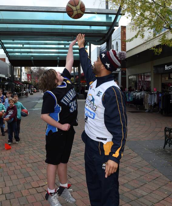 REACHING FOR THE SKY: Jacques Stone, 12, puts in a big jump to compete with the Miners' Roy Booker at a clinic in the Bridge Mall on Tuesday. Picture: Lachlan Bence