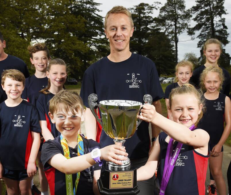BACK HOME: Jared Tallent with the Ballarat Racewalking Club while nephew, Brodie and niece, Jorja hold the trophy. Picture: Luka Kauzlaric