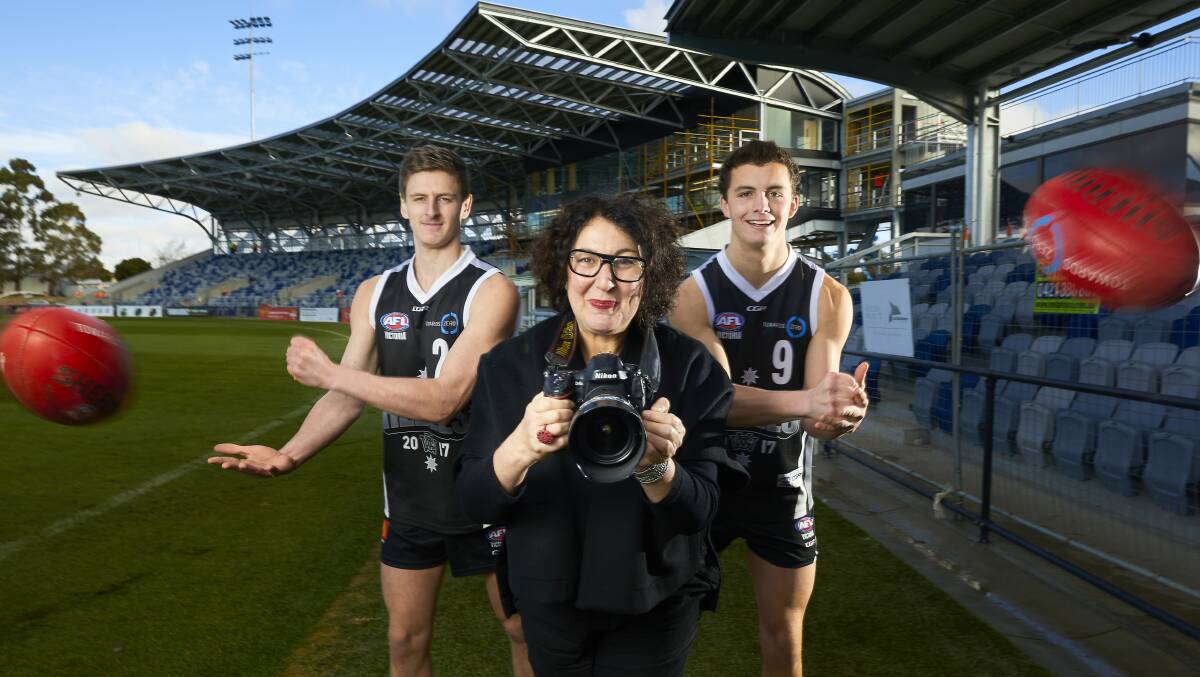 EYE ON THE BALL: Rebels players Callan Wellings and Flynn Appleby help Fiona Sweet marry footy with the Foto Festival. Picture: Luka Kauzlaric