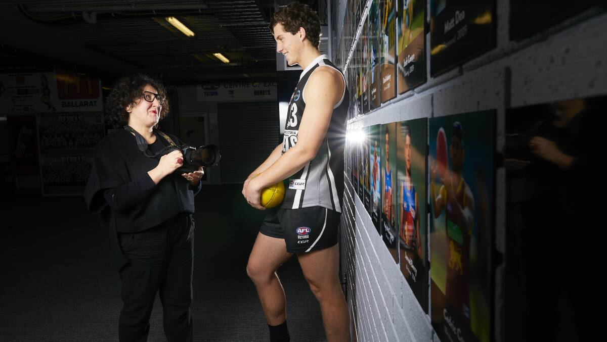 IN THE PICTURE: Ballarat International Foto Biennale director Fiona Sweet snaps Greater Western Victoria Rebels ruckman Lloyd Meek in front of the photo wall in the changerooms at Eureka Stadium. Picture: Luka Kauzlaric

