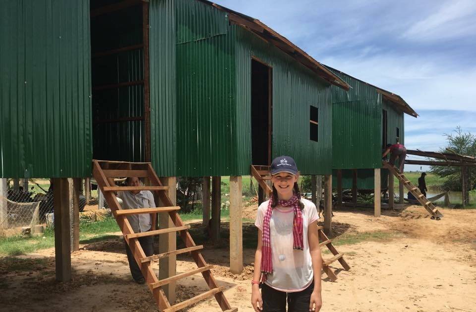 BASIC: Lauren McKenzie stands in front of some of the tin houses that she and other team members helped build for impoverished families on a trip to Cambodia in 2015.