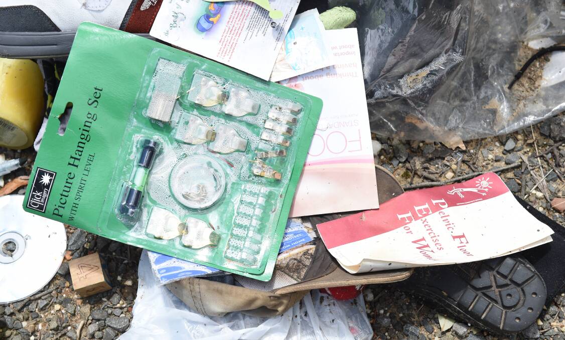 LITTER: Health care information, hardware and child-sized shoes spill out from a bag split open when tossed to the side of the road in Ballarat East.