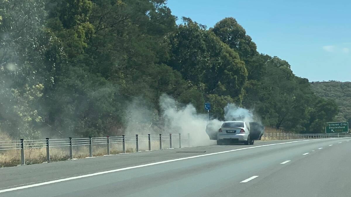 FIRE: Smoke billows from the car on the side of the Western Highway. Picture: Kate Healy