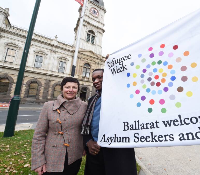 FLAGGED: Cr Belinda Coates and Fr Constantine Osuchukwu raise the flag to celebrate the start of National Refugee Week. Picture: Jeremy Bannister 