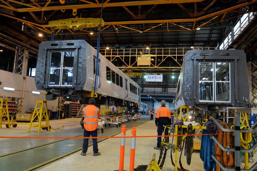 Lift: Alstom workers hoist a bodycar on Friday. Picture: Kate Healy