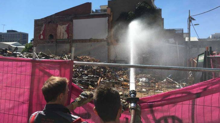 Firefighters dampen down building waste where Carlton's Corkman Irish Pub stood for 159 years, until it was illegally demolished on the weekend.  Photo: Supplied