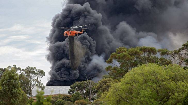 A water-bombing helicopter drops its load on the massive Broadmeadows tyre fire. Photo: Wayne Taylor