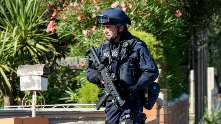An armed officer outside the house in Lavenia street St. Albans. Photo: Penny Stephens