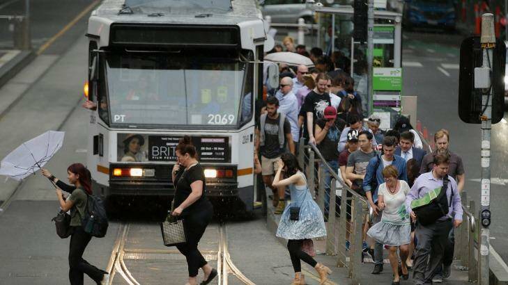 Commuters get off a tram in wild weather in Melbourne on Monday afternoon. Photo: Darrian Traynor