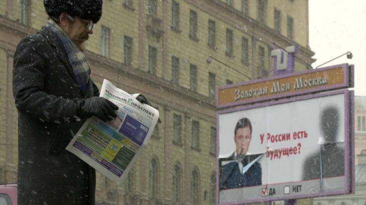 A man hands out free advertising newspapers in Moscow while behind him looms the Federal Security Service building. The Federal Security Service is the former KGB. Photo: Peter Dejong