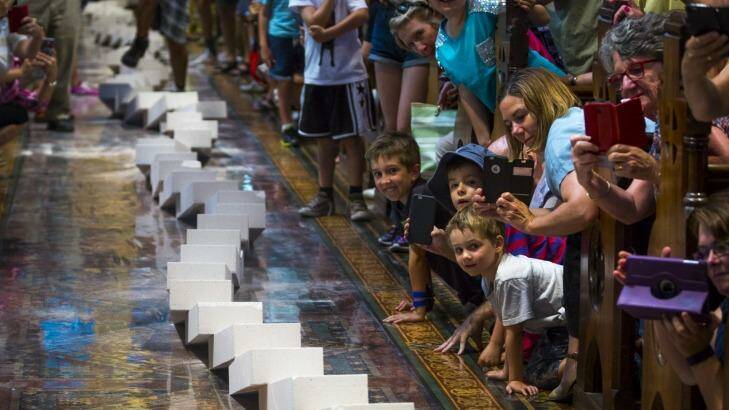 Melbournians gathered to watch a 2-kilometre domino train wind its way through the city, including the aisle of St Paul's Cathedral.  Photo: Chris Hopkins