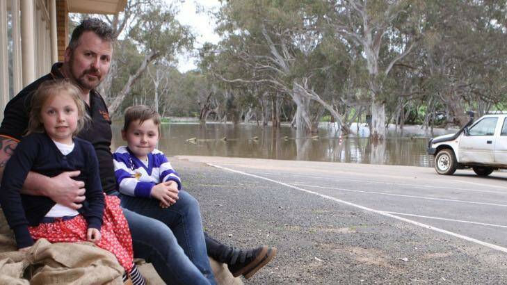 Glenelg Inn publican Troy Robbins and his children Marlee and Nate sit on sandbags outside the hotel at Casterton.  Photo: Everard Himmlereich