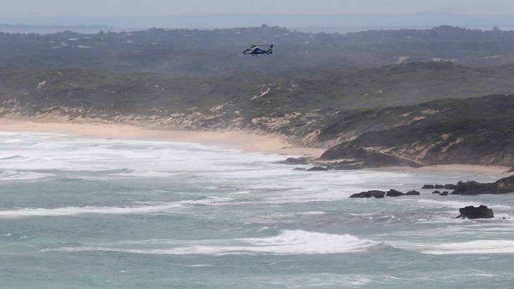 A search and rescue helicopter hovers over where two fishermen are missing in waters off Cape Schanck, on the Mornington Peninsula. Photo: Paul Jeffers