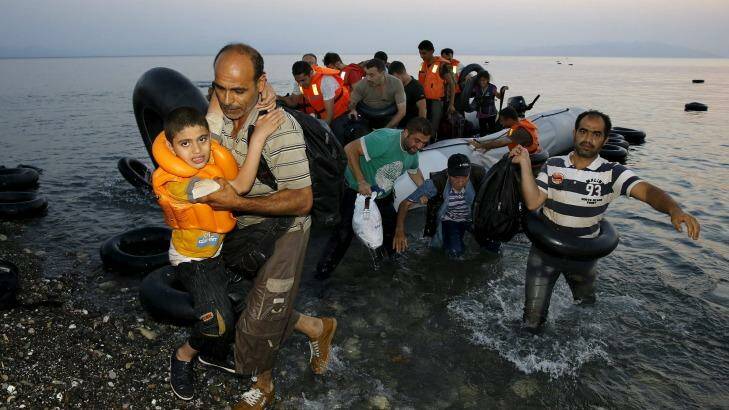 Syrian refugees carry their children as they arrive on a beach on the Greek island of Kos. Photo: Yannis Behrakis