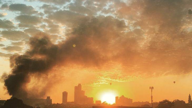 The sunrise in Melbourne and smoke from the South Melbourne fire at The Albion rooftop. Photo: Jonathan Beavan