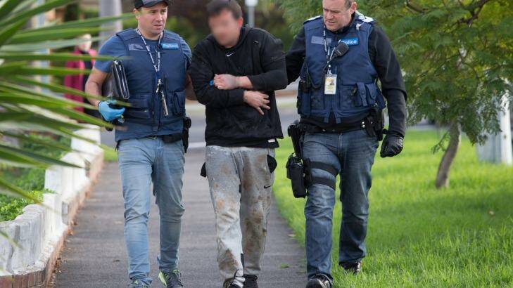 Police lead a man arrested in St Albans to a house in Essendon where further searches were carried out. Photo: Jason South