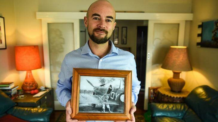 Duncan Williams holds a photo of his WWII RAAF pilot grandfather sitting on the wing of a Spitfire plane.  Photo: Justin McManus