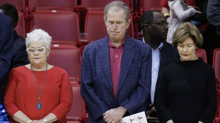 Former President George W Bush observes a moment of silence with his wife, Laura Bush (right), and others in support of the victims of the Paris terrorist attacks, before a college basketball game. Photo: LM Otero
