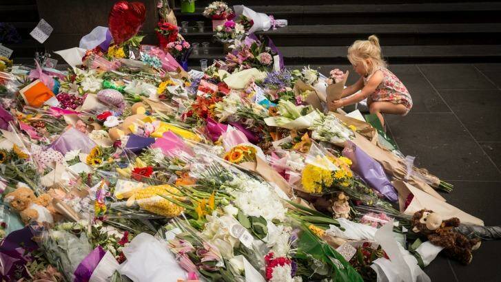 Two-year-old Jesse lays flowers at the tribute to the victims. Photo: Chris Hopkins