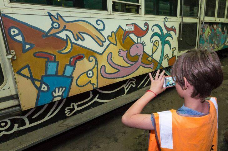 Henry taking a photo of Leunig's tram. The family of the late Melbourne artist David Larwill finally got to see his art tram, which he had thought lost, a year after VicTrack refused their request. Newport, Melbourne. January 4, 2018. Photo: Daniel Pockett